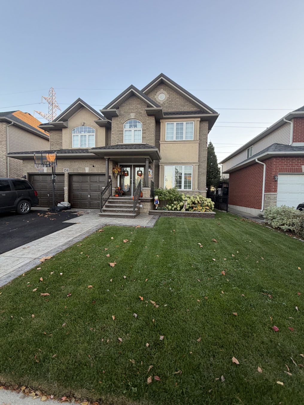 Even, dark-green sod lawn leading to a covered entry on a stone-front Hamilton home