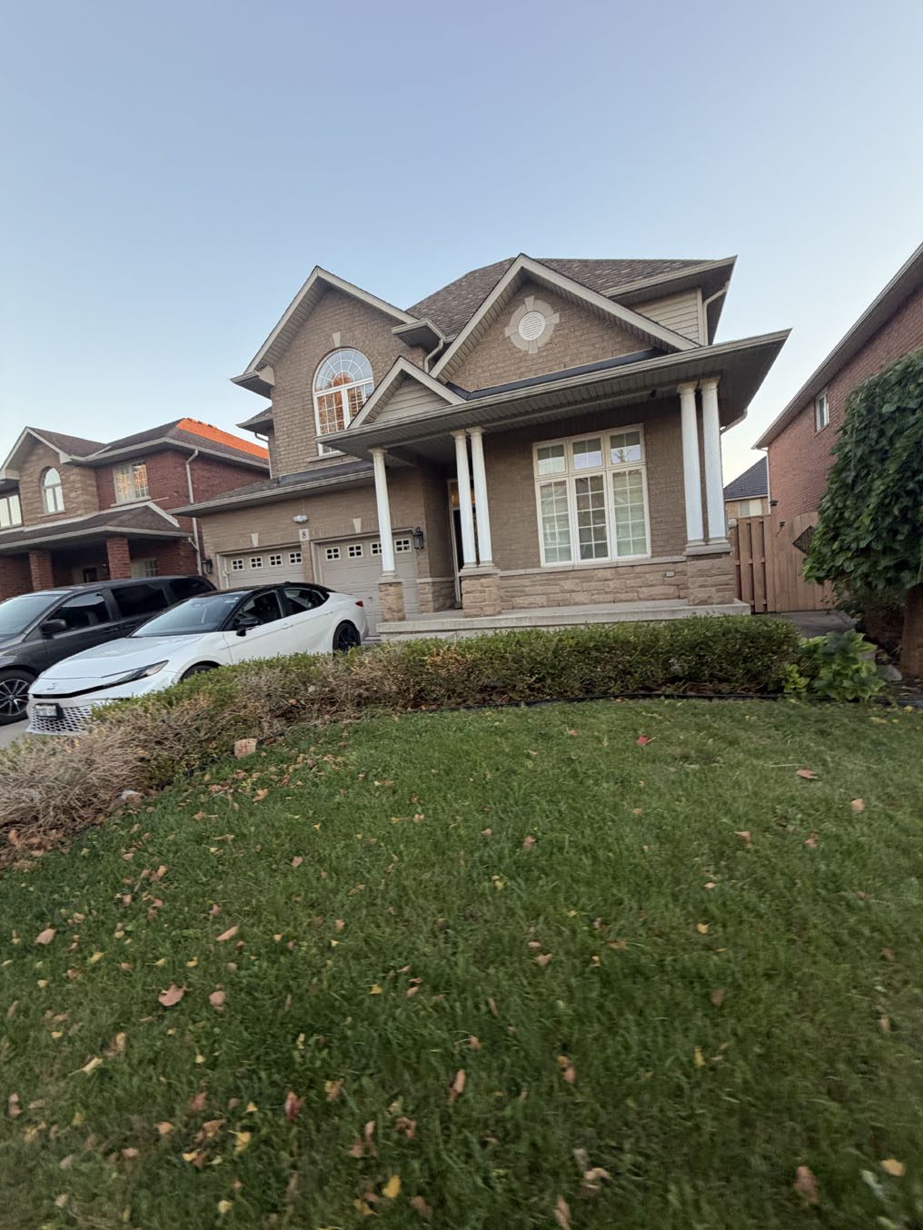 Front lawn edged by a low hedge at a home with a columned porch in Hamilton