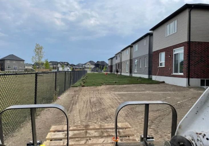 Services 4 Commercial sod installation in progress along a fence line behind newly constructed townhouses in Hamilton, Ontario
