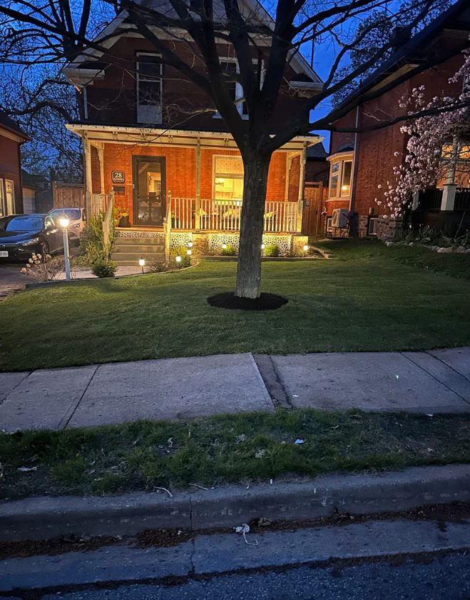 Gallery 4 A beautifully finished front yard featuring fresh green sod, a newly mulched tree ring, and landscape lighting at dusk in Corktown, Hamilton.