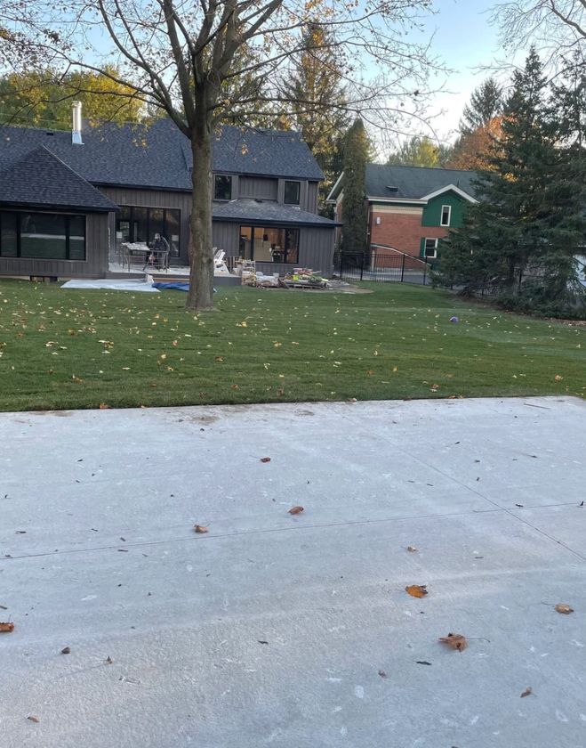 Gallery 30 Freshly installed green sod in a large residential backyard behind a modern dark grey home undergoing patio renovations in Downtown Grimsby.
