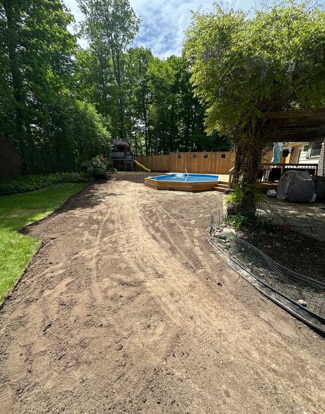 Gallery 23 Smoothly graded bare dirt with visible equipment tracks in a residential backyard, prepped for new sod installation near a pool in Central Burlington.