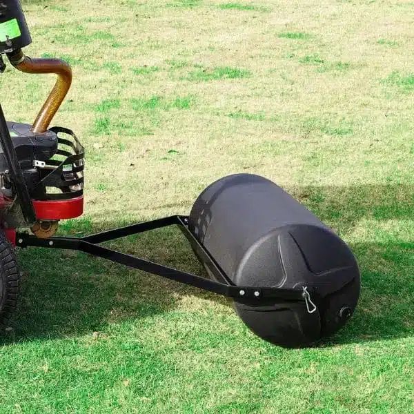 A black, water-filled lawn roller being towed across freshly installed green sod in Hamilton to ensure soil contact.